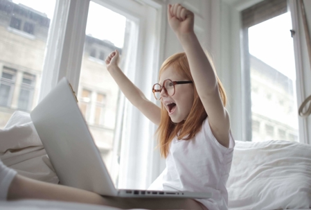 child cheering with laptop