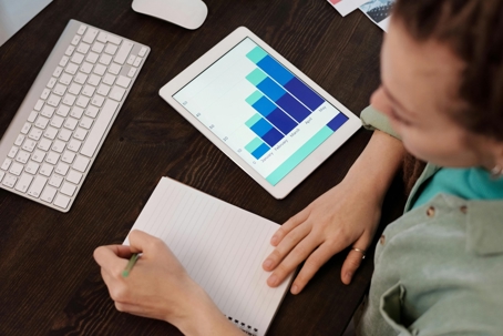 writing on a notepad with a tablet and graphs nearby