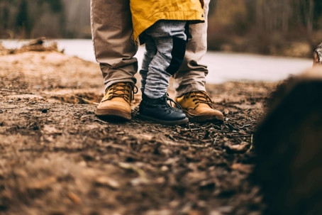child standing between parents feet