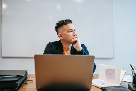 man sits with laptop pensively