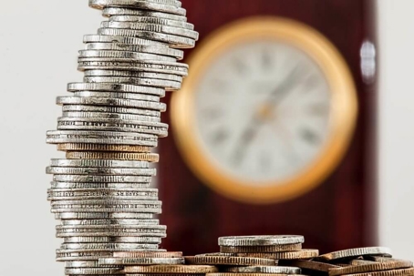 coins stacked with clock in the background