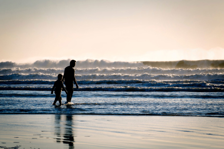 child and parent walking on the beach