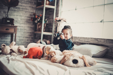 child sitting in bed with stuffed animals