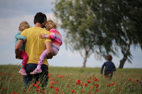 dad carrying children through field