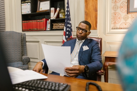 Business Man Sitting at Desk Reading a Paper